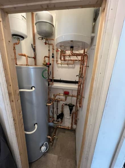 Heat pump hot-water cylinder and copper pipework neatly fitted in a compact cupboard