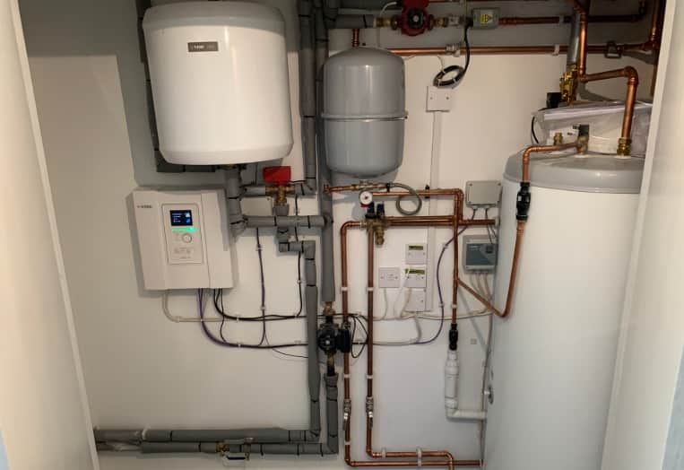 Indoor heat-pump plant room with cylinder, pumps and insulated copper pipework